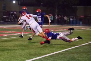 Hewitt-Trussville quarterback Zac Thomas is tripped up by a Vestavia defender. Thomas ran for 180 yards in the Huskies' win Friday night. Photo courtesy John Perry/Starnes Publishing
