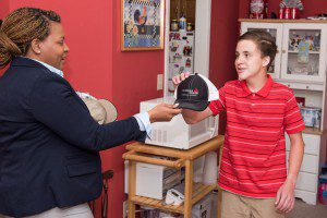 Alabama Power’s Toni Bishop presents a hat bearing the company logo to Spencer Harris, a teen with Asperger syndrome who aspires to work in the Alabama Power mailroom. (Nik Layman) 